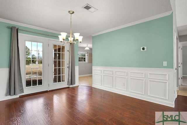 unfurnished dining area with a wealth of natural light, dark hardwood / wood-style floors, a textured ceiling, and a notable chandelier