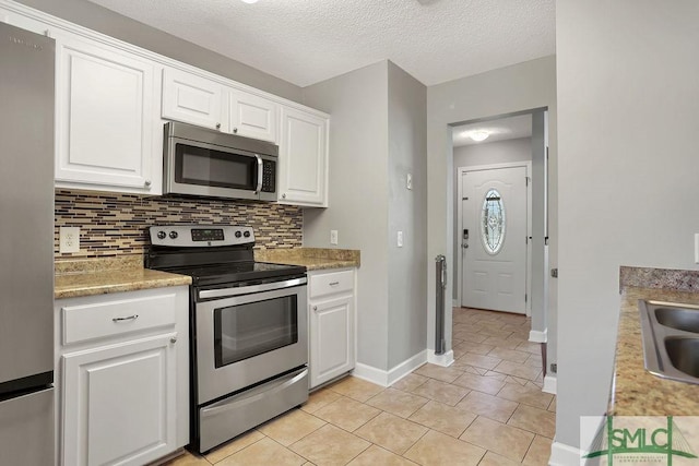 kitchen featuring appliances with stainless steel finishes, light tile patterned flooring, and white cabinetry