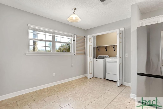 laundry area with washing machine and dryer, light tile patterned flooring, and a textured ceiling