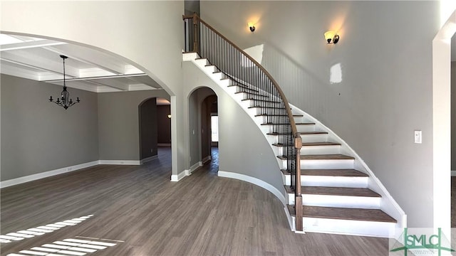 stairway featuring beam ceiling, coffered ceiling, a chandelier, and hardwood / wood-style flooring