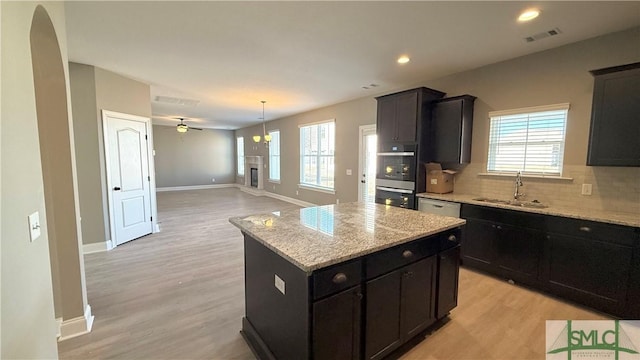 kitchen with light hardwood / wood-style floors, sink, light stone counters, and a kitchen island