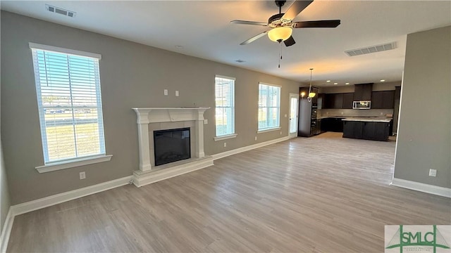 unfurnished living room featuring light wood-type flooring and ceiling fan with notable chandelier