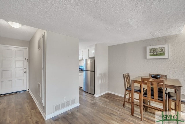 dining space featuring a textured ceiling and hardwood / wood-style flooring