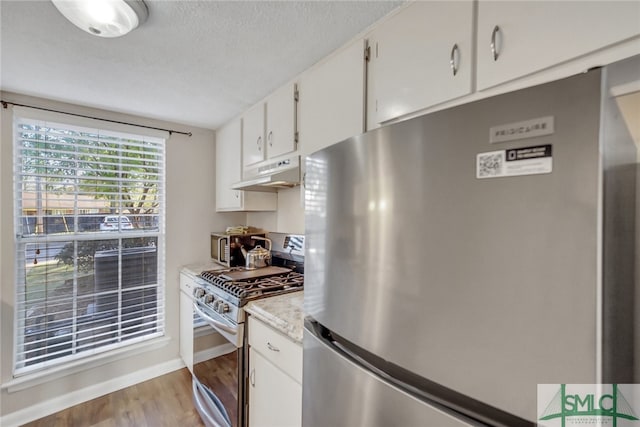 kitchen featuring a textured ceiling, white cabinets, light hardwood / wood-style flooring, and stainless steel appliances