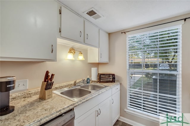 kitchen with hardwood / wood-style floors, stainless steel dishwasher, white cabinets, and sink