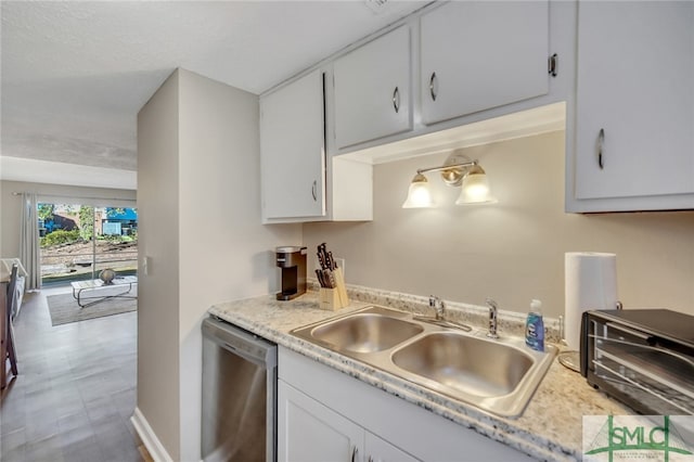 kitchen featuring dishwasher, sink, and white cabinetry