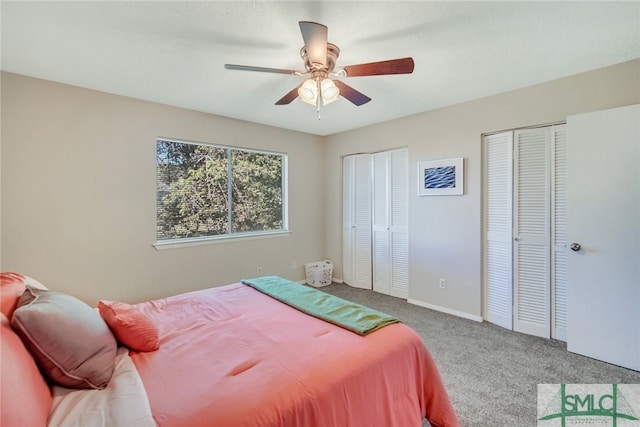 carpeted bedroom featuring ceiling fan and two closets