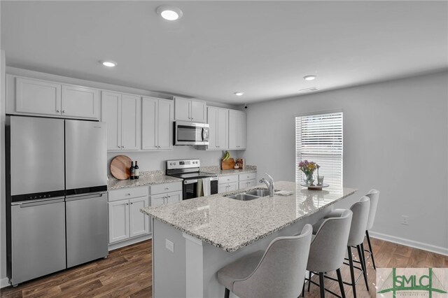 kitchen with dark hardwood / wood-style floors, a center island with sink, sink, white cabinetry, and stainless steel appliances