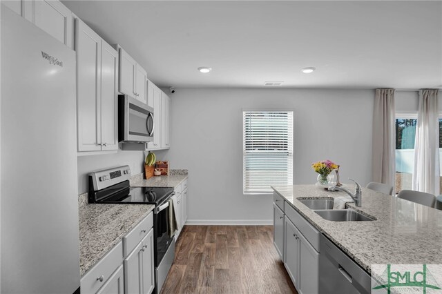 kitchen with stainless steel appliances, dark wood-type flooring, light stone countertops, white cabinets, and sink