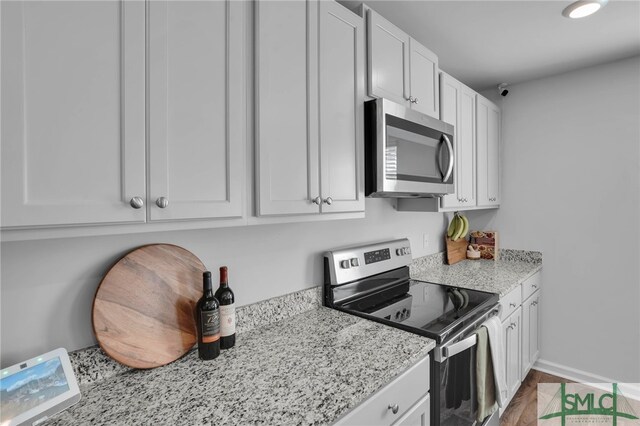 kitchen featuring white cabinets, appliances with stainless steel finishes, and light stone counters