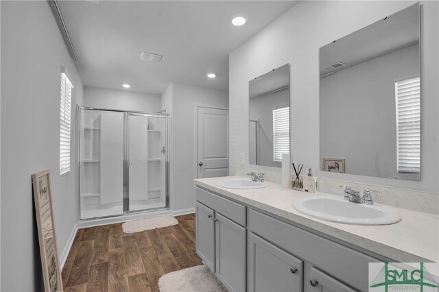 bathroom with a healthy amount of sunlight, a shower with shower door, hardwood / wood-style flooring, and vanity