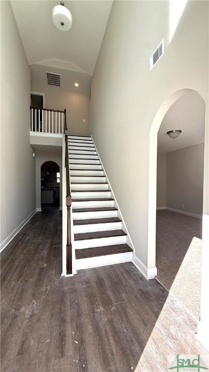 stairway with high vaulted ceiling and hardwood / wood-style floors