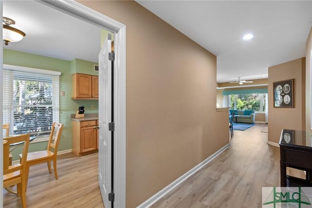 hall with a healthy amount of sunlight and light hardwood / wood-style floors