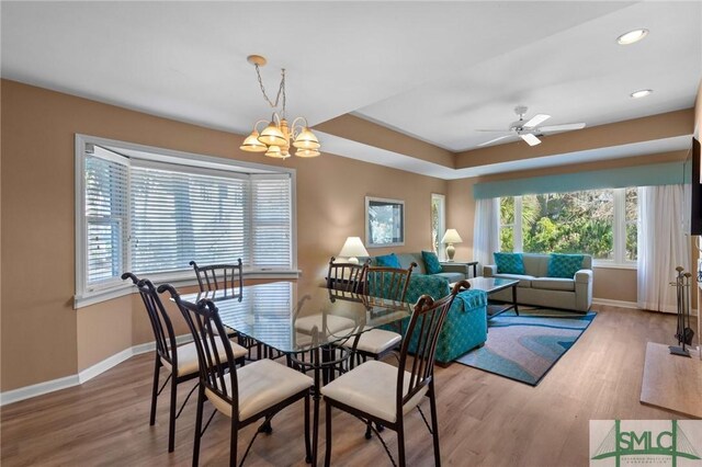 dining area featuring a healthy amount of sunlight, ceiling fan with notable chandelier, and wood-type flooring