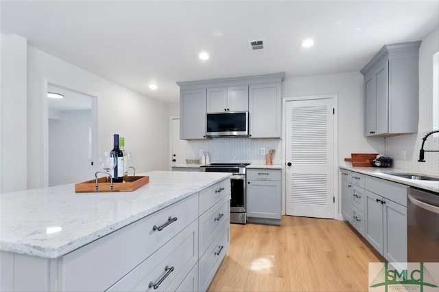 kitchen with stainless steel appliances, backsplash, a kitchen island, and gray cabinets