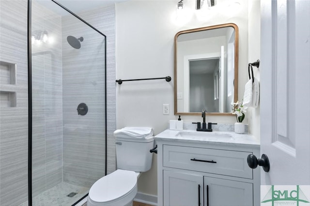 bathroom featuring toilet, vanity, and tiled shower