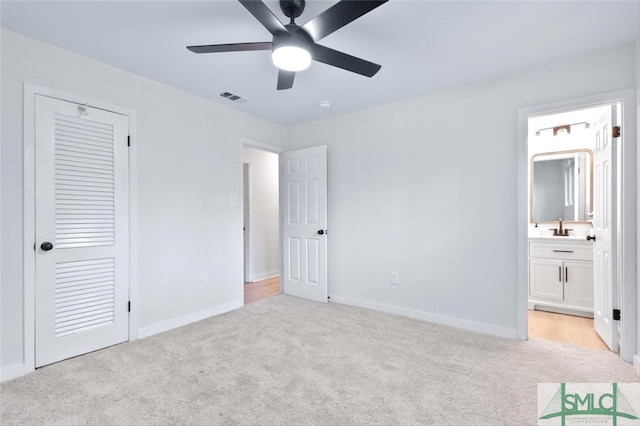 unfurnished bedroom with ceiling fan, sink, connected bathroom, light carpet, and a closet