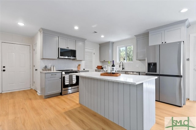 kitchen with a center island, sink, light hardwood / wood-style flooring, appliances with stainless steel finishes, and gray cabinetry