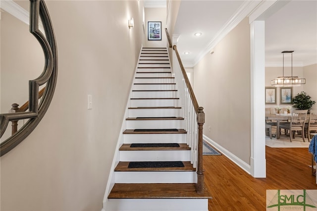 stairway with wood-type flooring and crown molding