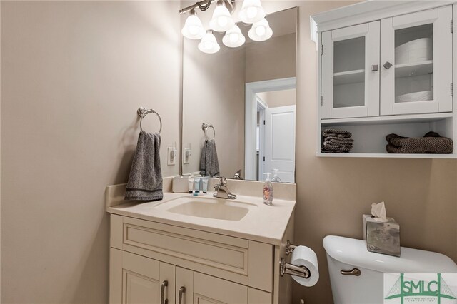 bathroom with toilet, vanity, and a notable chandelier