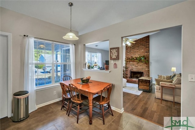 dining area featuring lofted ceiling, a brick fireplace, a healthy amount of sunlight, and ceiling fan