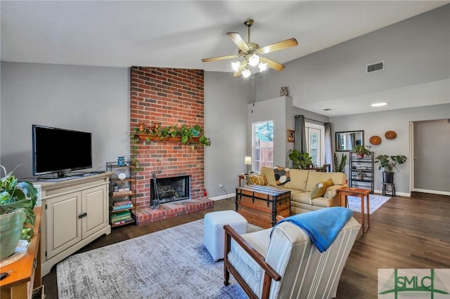 living room with vaulted ceiling, ceiling fan, a fireplace, and dark wood-type flooring