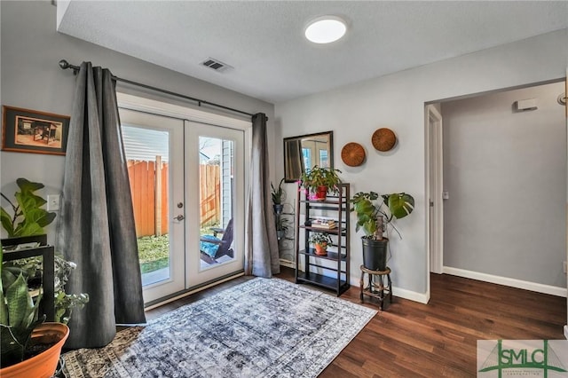 doorway to outside with a textured ceiling, dark hardwood / wood-style floors, and french doors