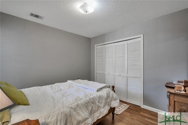 bedroom featuring a closet, dark wood-type flooring, and a textured ceiling