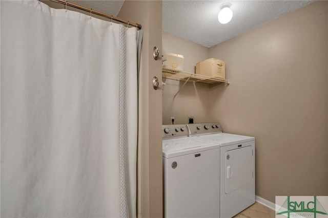 clothes washing area with separate washer and dryer and a textured ceiling