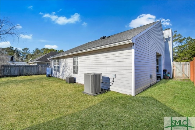 rear view of property featuring central AC and a lawn