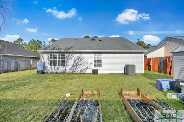 rear view of house with central AC unit and a lawn