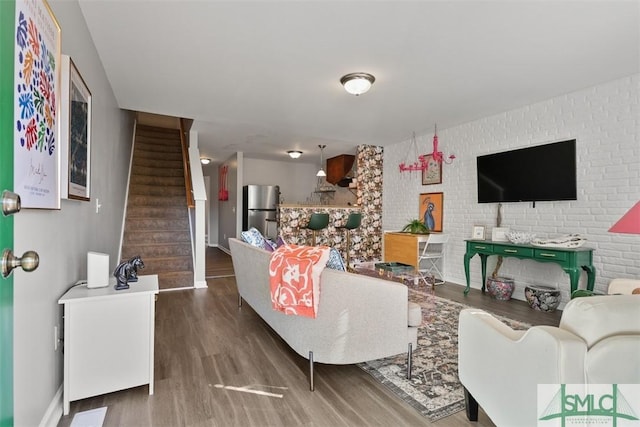 living room with dark hardwood / wood-style floors and brick wall