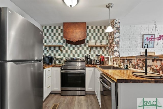 kitchen with wooden counters, appliances with stainless steel finishes, sink, and white cabinetry