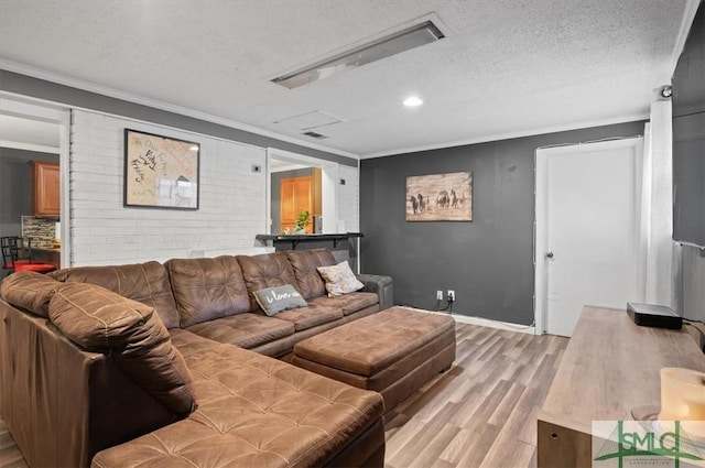 living room featuring a textured ceiling, ornamental molding, and light wood-type flooring