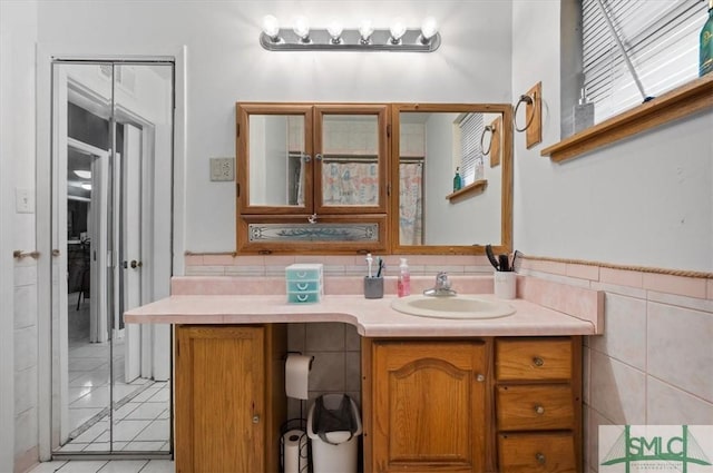 bathroom with tile walls, vanity, and tile patterned flooring