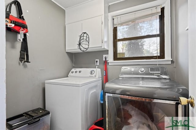 clothes washing area featuring washing machine and clothes dryer and cabinets