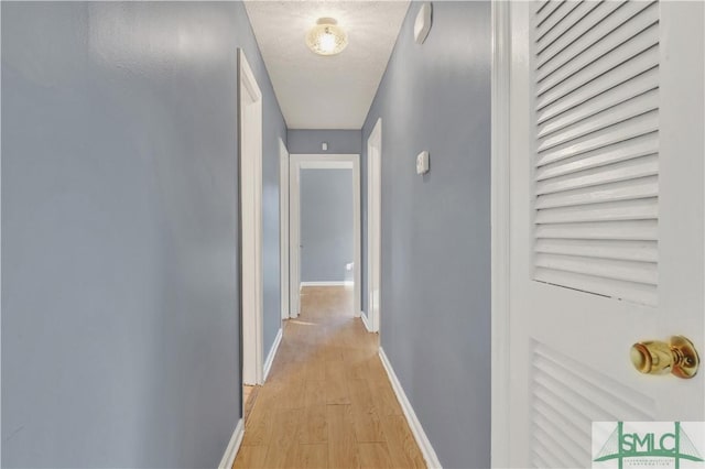 corridor with light hardwood / wood-style floors and a textured ceiling