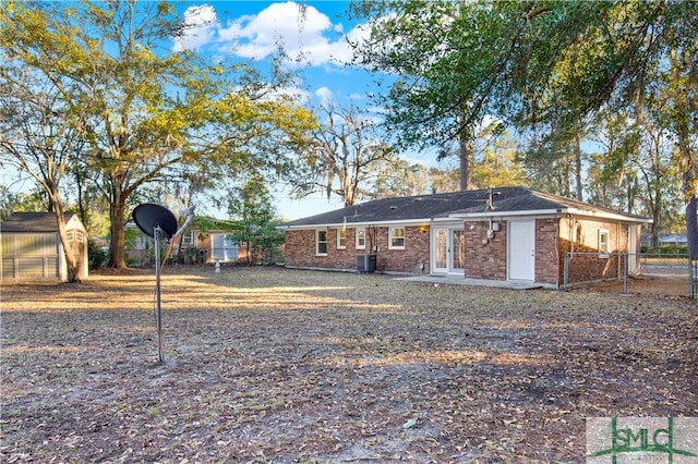 back of house featuring central AC unit and a storage unit