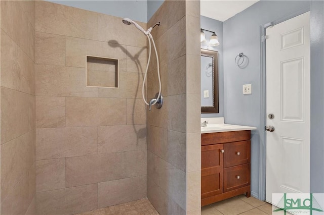 bathroom with a tile shower, vanity, and tile patterned flooring