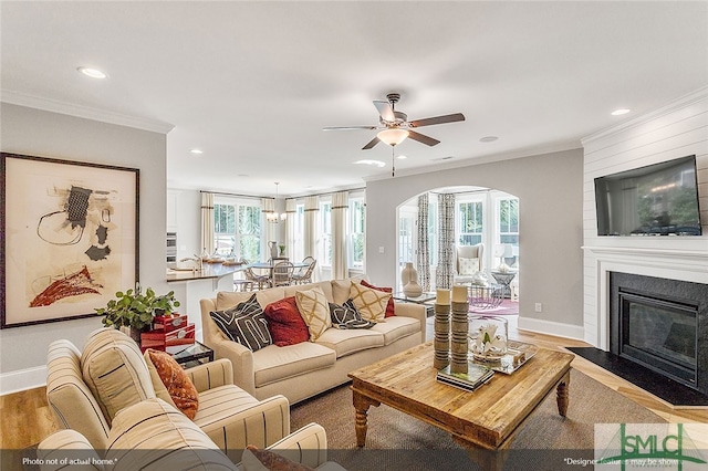 living room with crown molding, baseboards, recessed lighting, and wood finished floors