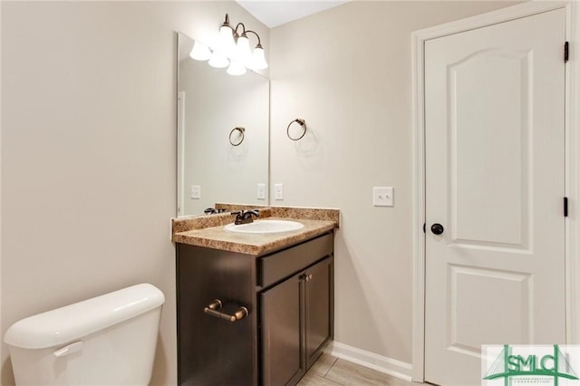 half bath with toilet, vanity, and baseboards