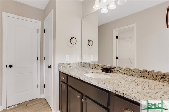 bathroom with a walk in closet, wood finished floors, and vanity