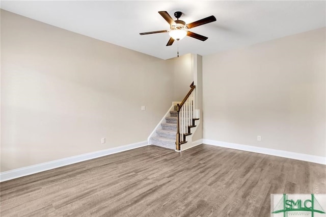 spare room with ceiling fan, stairs, baseboards, and wood finished floors