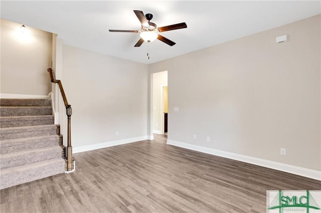 unfurnished living room with a ceiling fan, stairs, baseboards, and wood finished floors