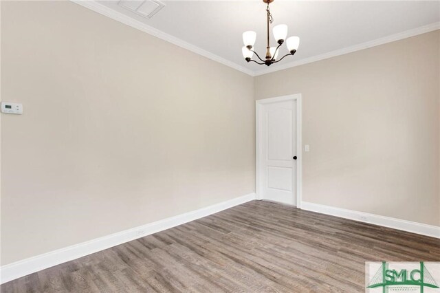 spare room featuring a chandelier, crown molding, and hardwood / wood-style flooring