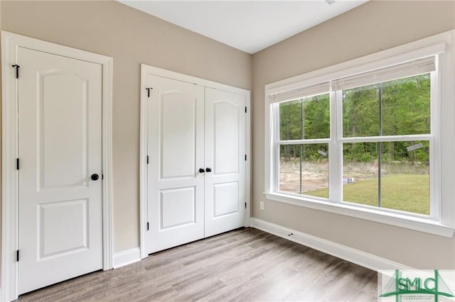 unfurnished bedroom featuring light wood-style floors, a closet, and baseboards