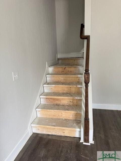 staircase featuring wood finished floors and baseboards