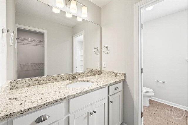 57 Oakmont Dr, Guyton, GA 31312 - bathroom with vanity, toilet, tile patterned flooring, baseboards, and a walk in closet