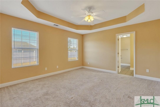 carpeted spare room featuring ceiling fan and a raised ceiling