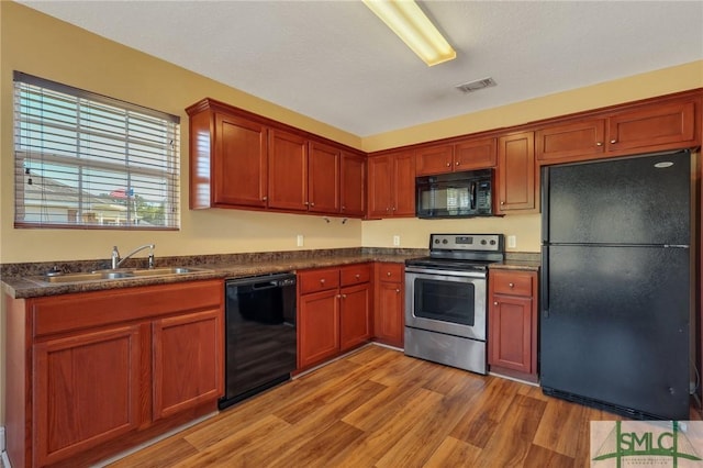 kitchen with black appliances, light wood-type flooring, and sink